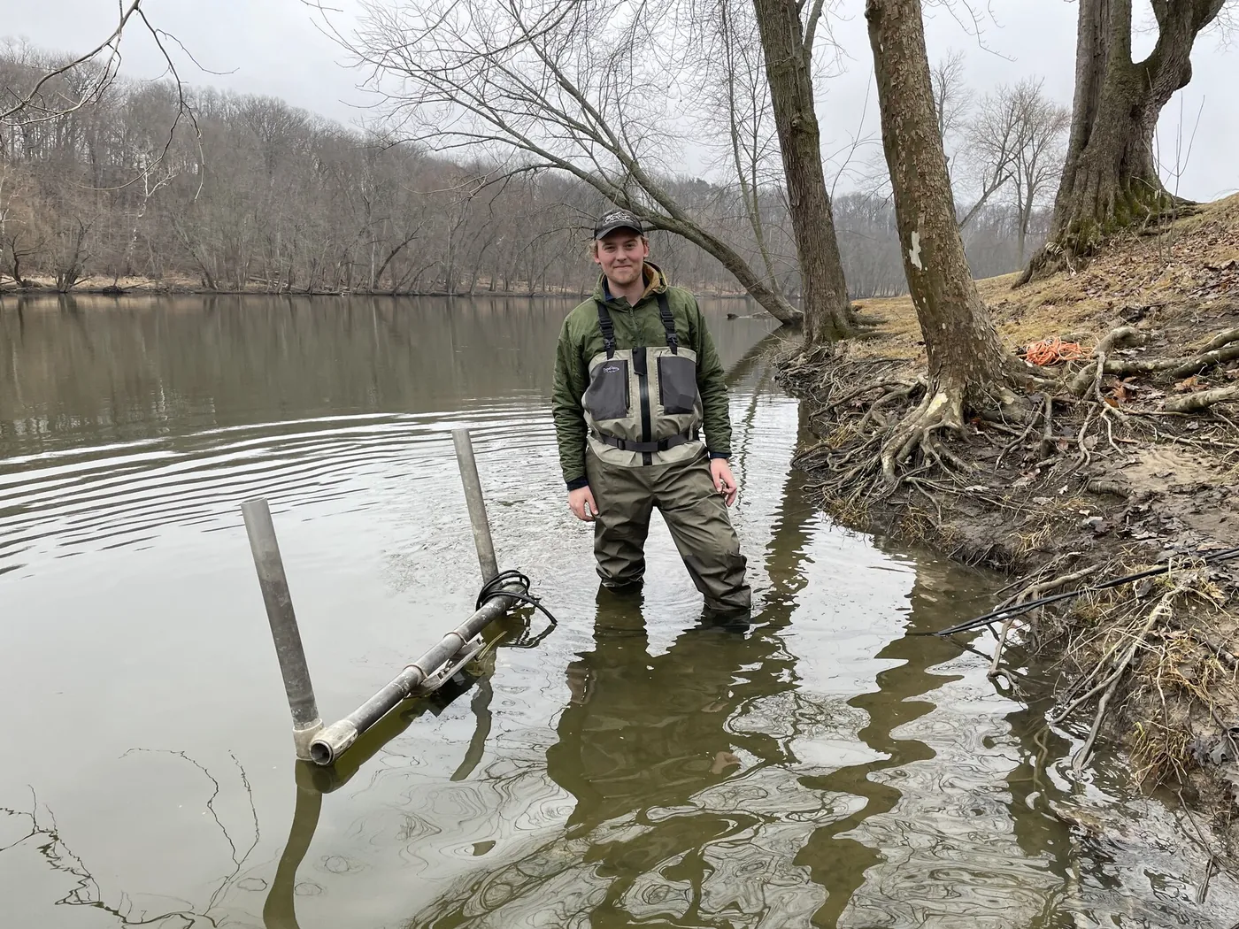 Eamonn Powers in chest waders in the Grand River beside a deployed sonar mount.